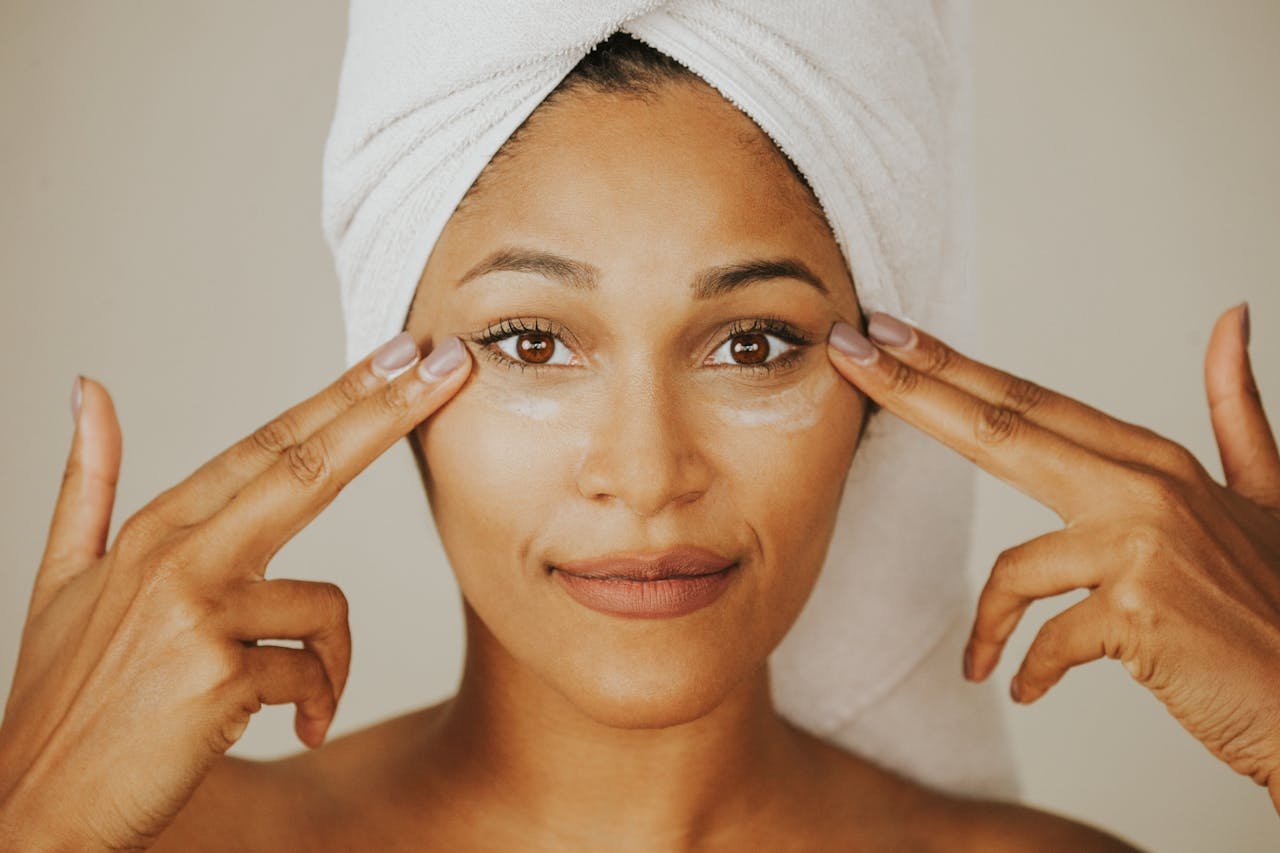about-img Woman applying facial cream with a towel wrapped on her head, highlighting skincare routine.